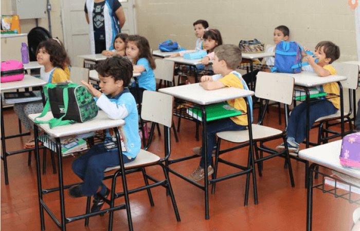 Turma em sala de aula, várias crianças com os pés longe do chão
